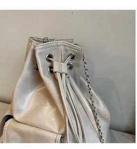 Detail of cream leather bucket bag with silver eyelets and drawstring closure mechanism