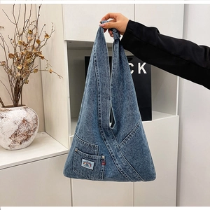 Detail of vintage washed denim tote bag featuring a decorative pocket and rainbow patch