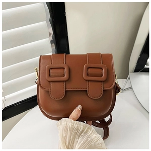 Détail d'un sac besace marron vintage avec deux boucles carrées décoratives sur le rabat