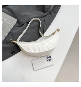 Close-up of pearl white crescent bag with smooth glossy finish and gold metal hardware