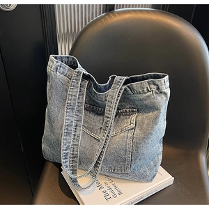 Detail of light blue denim tote bag with front pocket placed on a modern black chair