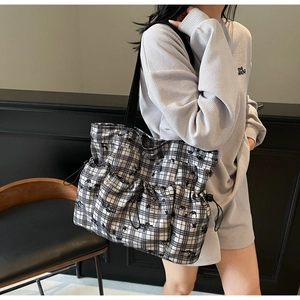 Detail of checkered canvas tote bag featuring cartoon prints and side drawstring design