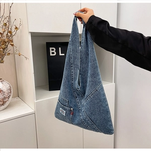 Detail view of washed denim tote bag featuring utility pockets and rainbow patch accent