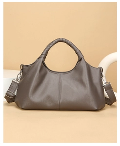 Detail of taupe leather tote featuring woven handles and adjustable shoulder strap