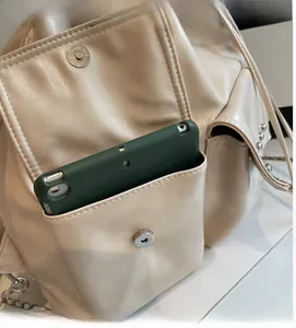 Detail showing magnetic pocket capacity on beige PU leather backpack with silver hardware