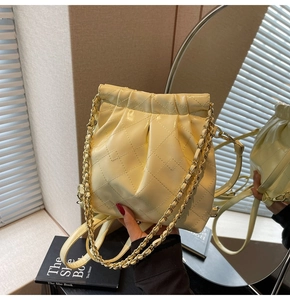 Detailed view of cream quilted bucket bag with gold chain strap in a mirror reflection