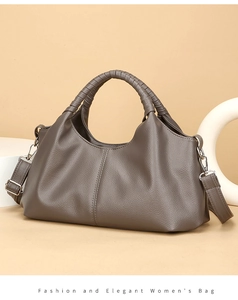 Detailed close-up of taupe leather handbag featuring woven handle and textured finish