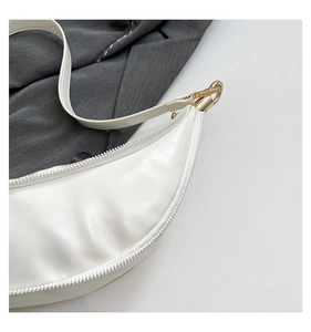 Detail shot of the sleek white leather crescent bag with elegant golden hardware accents