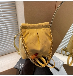 Detail of cream quilted bucket bag with gold chain strap and elegant pleated leather finish