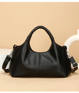 Detail of black pebbled leather handbag with braided handle and silver hardware