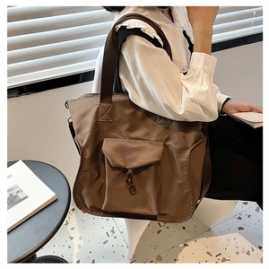 Detail of dark brown nylon tote bag featuring front flap pocket and decorative metal chain