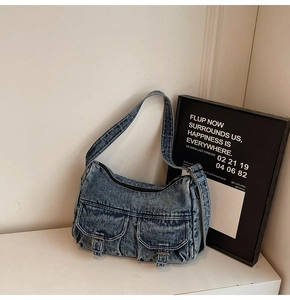 Detail of vintage blue denim shoulder bag with dual utility pockets and metal buckles