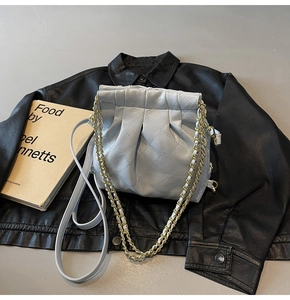 Detail showing blue quilted bucket bag with gold chain strap and drawstring closure