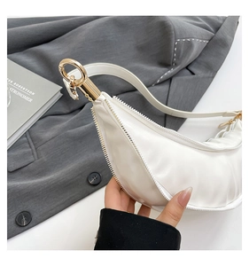 Detailed close-up of white crescent bag showing golden metal ring and soft leather texture