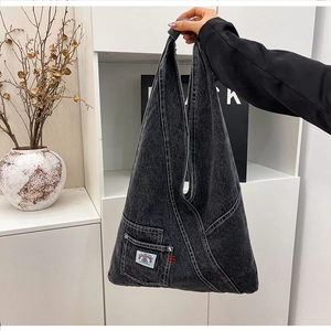Detail of grey washed denim hobo bag with contrast stitching and branded textile label