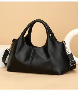 Close-up of black litchi texture leather bag with woven handles and silver hardware