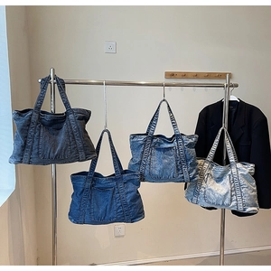 Detail showing vintage denim tote bags in four washed shades on a metal rack