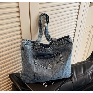 Close-up of vintage denim tote bag featuring a front pocket with silver metal buckle