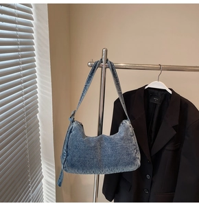 Detail of blue denim hobo bag showing retro washed texture and decorative knot on the side