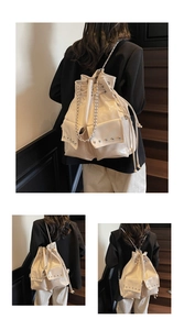 Detail of cream drawstring backpack with silver rivets and metal chain shoulder straps