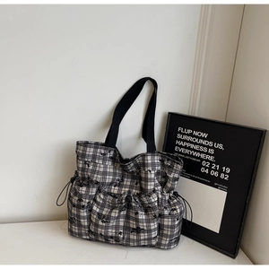 Detail of checkered tote bag with three drawstring pockets and black woven handles