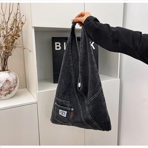 Detailed side view of washed denim tote with zipper pocket and colorful woven label