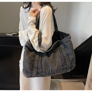 Detail of dark denim tote bag featuring white contrast stitching and large front pocket