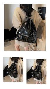 Detail of black glossy PU leather backpack with rivet-studded pockets and chain straps
