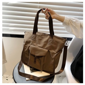 Detailed view of brown nylon tote bag with front pocket, chain accent and adjustable strap