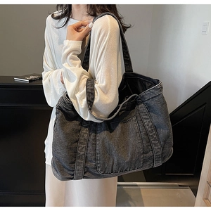 Detail of large vintage washed denim tote bag with front pocket and shoulder straps