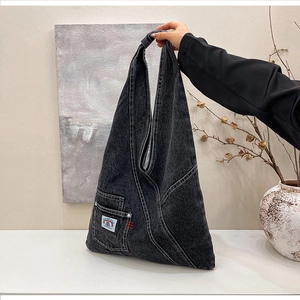 Macro detail of washed denim bag featuring utility pocket and embroidered label
