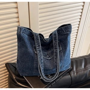 Close-up of a vintage dark blue denim tote bag with a metallic button front pocket