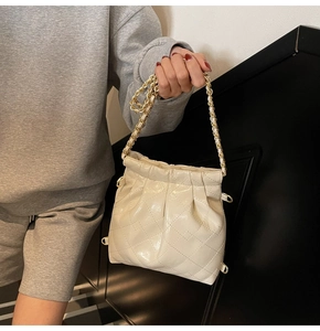Detail of cream quilted bucket bag with golden chain handle and soft faux leather texture