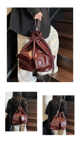 Detail view of burgundy drawstring bucket bag with studded pockets and chain strap