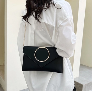 Détail de pochette enveloppe noire élégante avec boucle anneau dorée et bandoulière