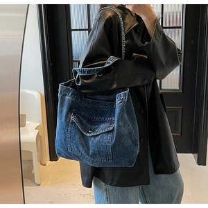 Detail of vintage denim tote bag showing washed fabric texture and front flap pocket with button