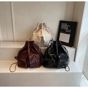 Detailed shot of drawstring bucket bags in beige, burgundy, and black with stud pockets