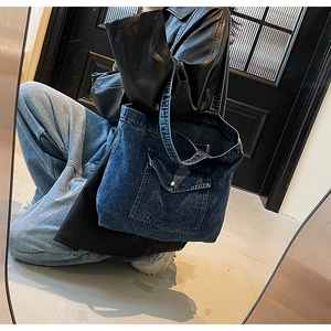 Detail of vintage denim tote bag featuring a front pocket with silver metal buckle