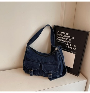 Close-up of deep blue denim hobo bag featuring dual cargo pockets with metal buckles