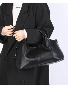 Detail shot of black pebbled leather tote bag with silver metal rings on a model