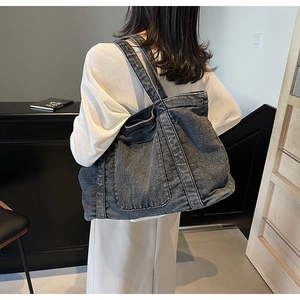 Detail of a large charcoal wash denim tote bag showing texture and front utility pockets