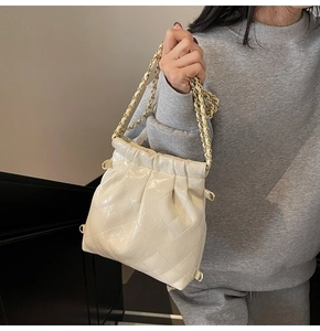 Detail of quilted texture and gold chain strap on the beige bucket bag for women