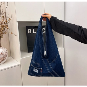 Detail view of deep blue denim hobo bag featuring white topstitching and knotted handle