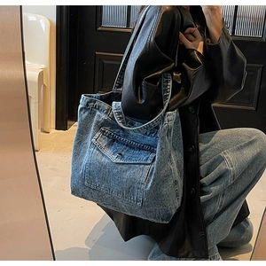 Detail of vintage denim tote bag showing workwear style front flap pocket with button