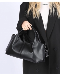 Close-up of black lychee grain leather tote bag with woven handles and detachable strap