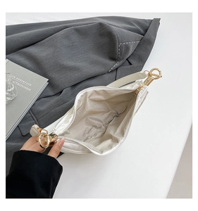 Detail shot of white dumpling bag showing interior space with gold zipper and hardware