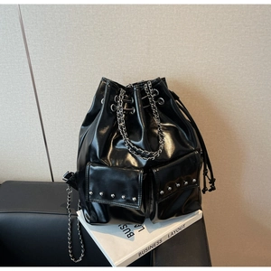 Detailed view of black patent leather bucket bag with silver studs and chain drawstring
