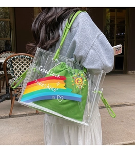 Detail of transparent rainbow tote bag with green drawstring pouch and graphic prints
