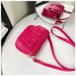 Gros plan d'un sac besace rose avec boucles dorées et reflet dans un miroir rond