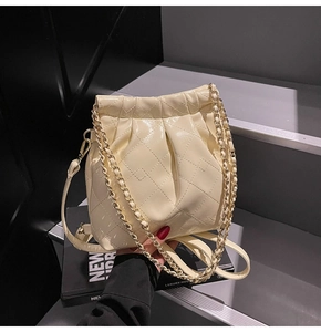 Detail of cream quilted leather bucket bag with gold chain strap on black display